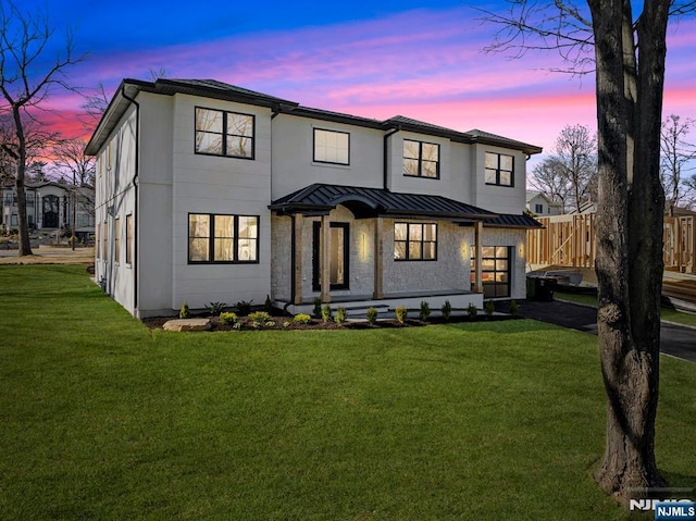 view of front of house with a standing seam roof, aphalt driveway, fence, a front yard, and metal roof