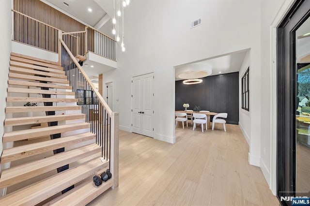 stairs with visible vents, baseboards, wood finished floors, and a towering ceiling