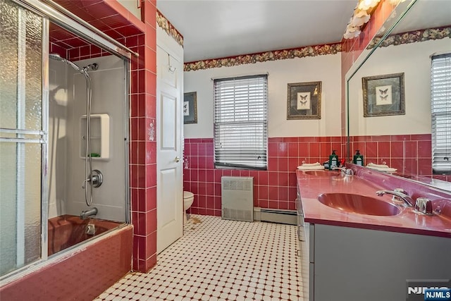 full bathroom featuring toilet, vanity, shower / bath combination with glass door, tile walls, and a baseboard radiator