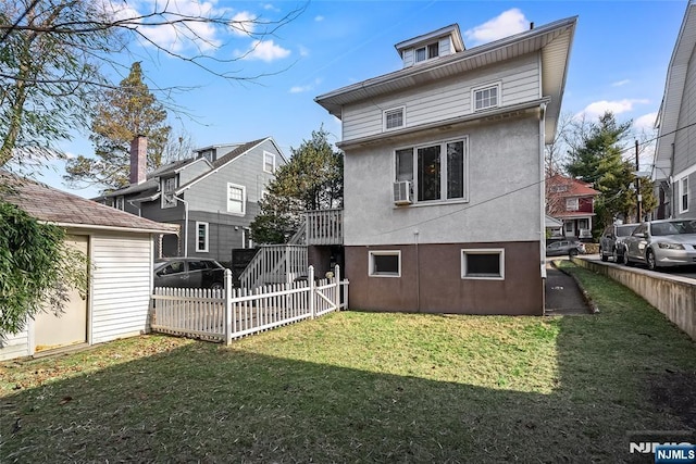 rear view of house with stairway, a yard, fence, and stucco siding