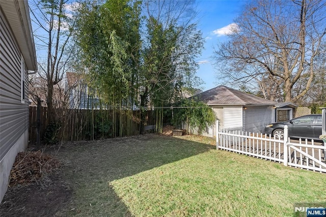 view of yard featuring a garage, an outbuilding, and a fenced backyard