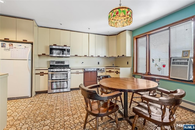 kitchen featuring cooling unit, light countertops, cream cabinetry, appliances with stainless steel finishes, and pendant lighting