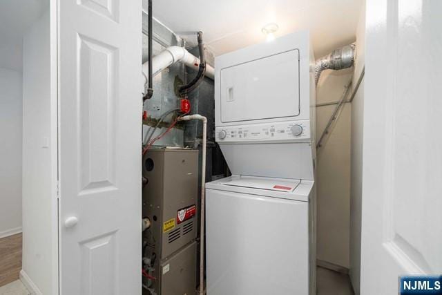 laundry area featuring baseboards, stacked washer and dryer, and laundry area