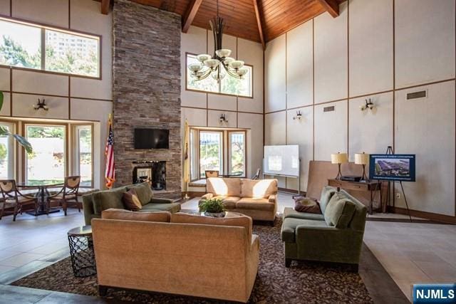 living room with beamed ceiling, wooden ceiling, a stone fireplace, and high vaulted ceiling