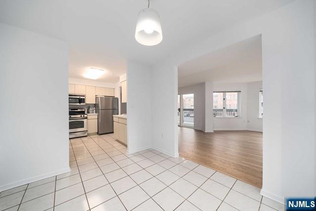 kitchen with light tile patterned flooring, hanging light fixtures, light countertops, appliances with stainless steel finishes, and open floor plan