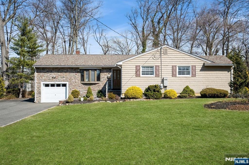 single story home with aphalt driveway, a garage, a front yard, and a chimney