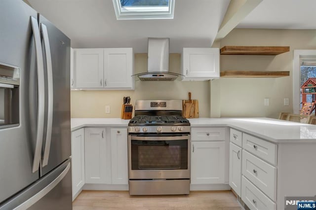 kitchen featuring wall chimney range hood, light countertops, a peninsula, appliances with stainless steel finishes, and white cabinetry