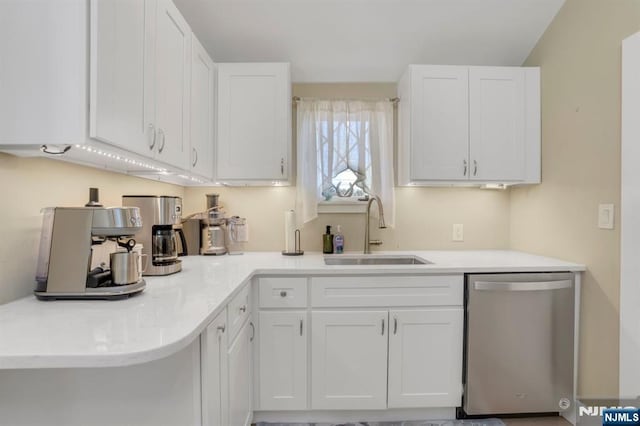 kitchen with a sink, white cabinets, light countertops, and stainless steel dishwasher