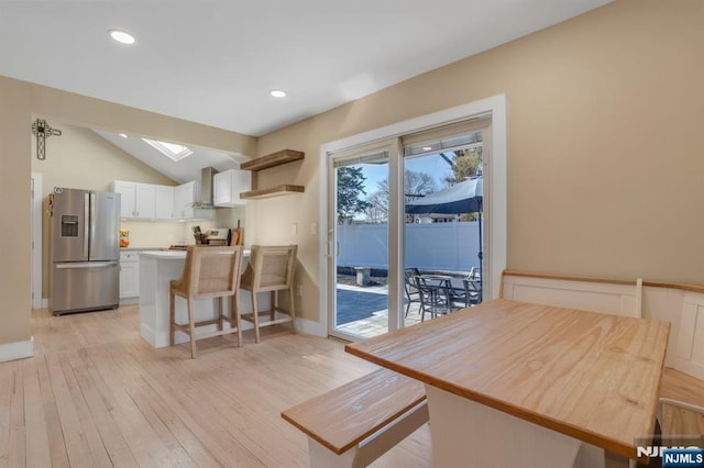 dining space featuring recessed lighting, light wood-type flooring, vaulted ceiling with skylight, and baseboards