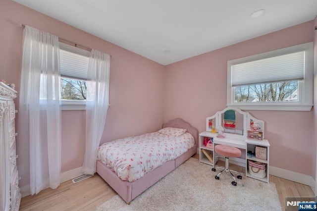 bedroom with visible vents, baseboards, and wood finished floors