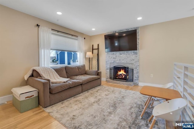 living area with recessed lighting, a fireplace, baseboards, and wood finished floors