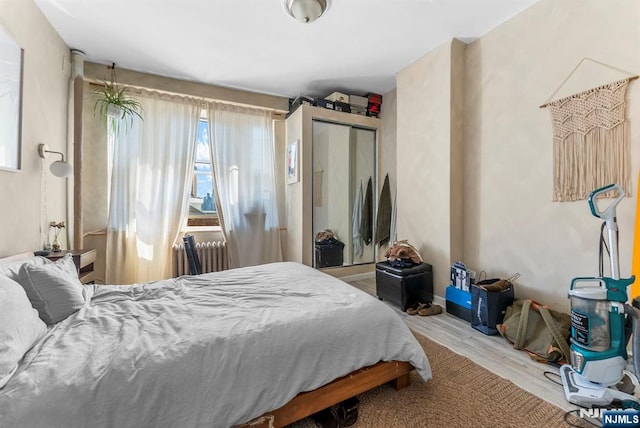 bedroom featuring a closet, radiator, and wood finished floors