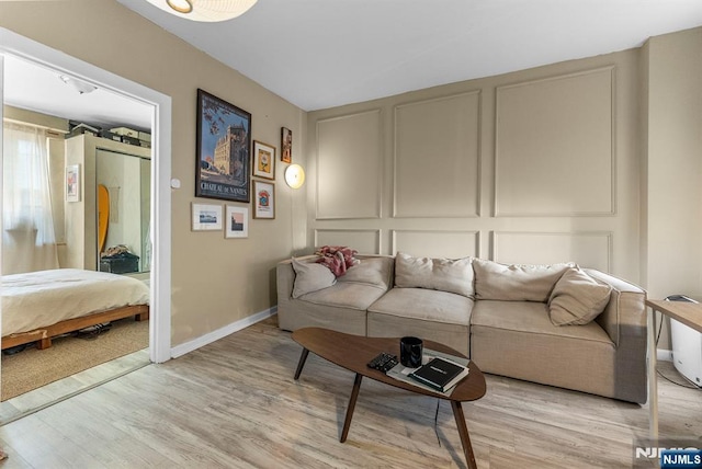 living room with a decorative wall, baseboards, and light wood-type flooring