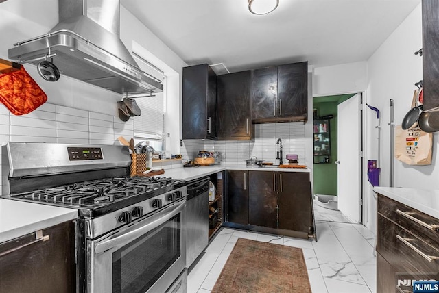 kitchen with backsplash, light countertops, marble finish floor, stainless steel appliances, and wall chimney exhaust hood