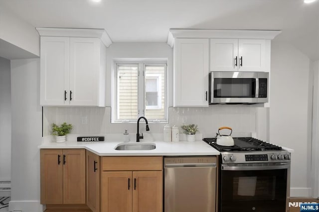 kitchen featuring a sink, decorative backsplash, light countertops, and stainless steel appliances