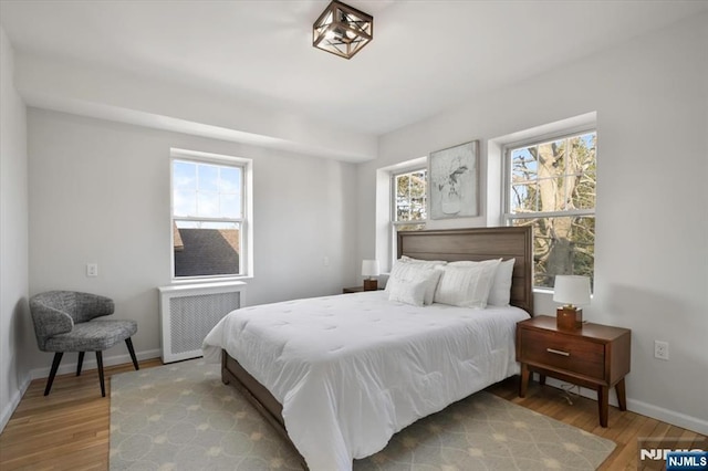 bedroom featuring radiator heating unit, baseboards, and wood finished floors