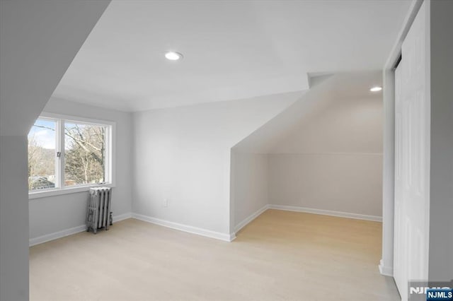 additional living space with lofted ceiling, recessed lighting, light wood-style floors, radiator, and baseboards