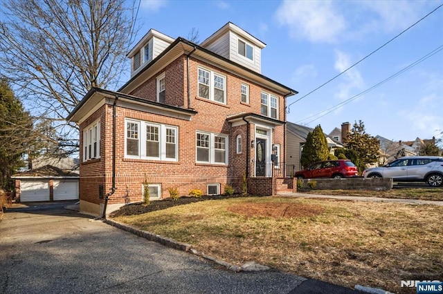 traditional style home featuring a garage, a front lawn, an outbuilding, and brick siding