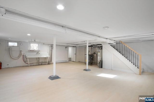 below grade area featuring stairs, wood finished floors, and water heater