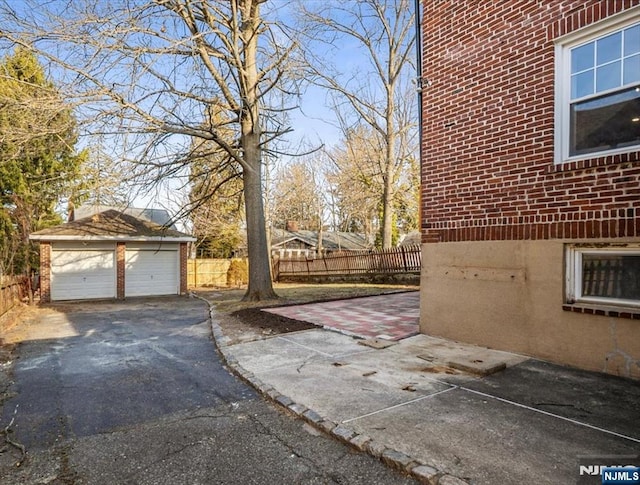 view of home's exterior with brick siding, a detached garage, and fence