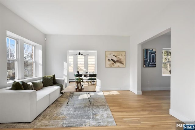 living area with light wood-style flooring, baseboards, and ceiling fan