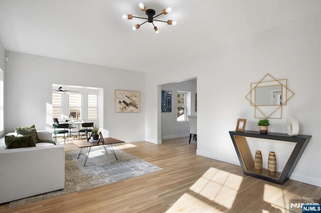 living area featuring a chandelier, baseboards, and wood finished floors