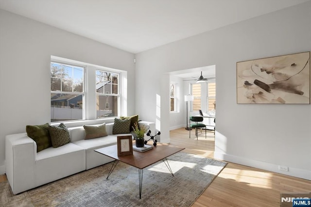 living room with a ceiling fan, wood finished floors, and baseboards