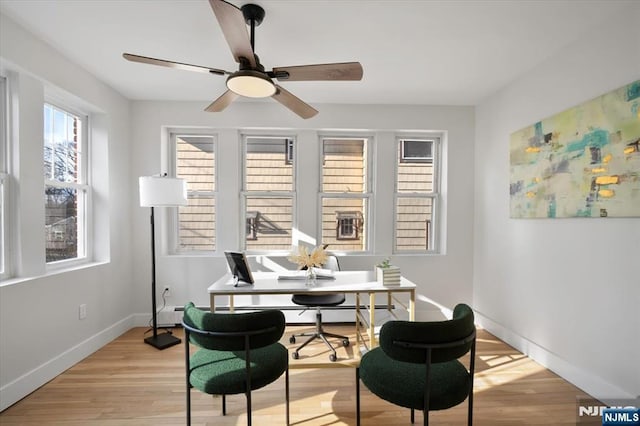 dining space with light wood finished floors, a ceiling fan, and baseboards