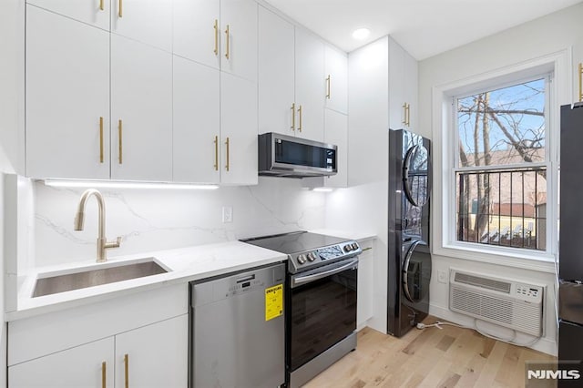 kitchen featuring light stone counters, a sink, an AC wall unit, appliances with stainless steel finishes, and backsplash