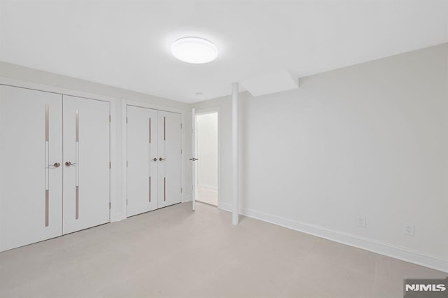 unfurnished bedroom featuring baseboards and two closets