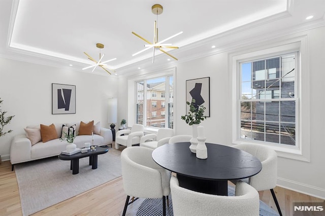 dining area featuring a chandelier, light wood finished floors, crown molding, and a tray ceiling