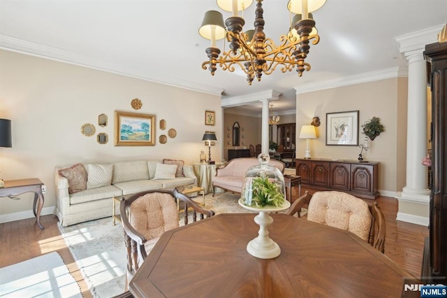 dining room featuring wood finished floors, crown molding, decorative columns, baseboards, and a chandelier