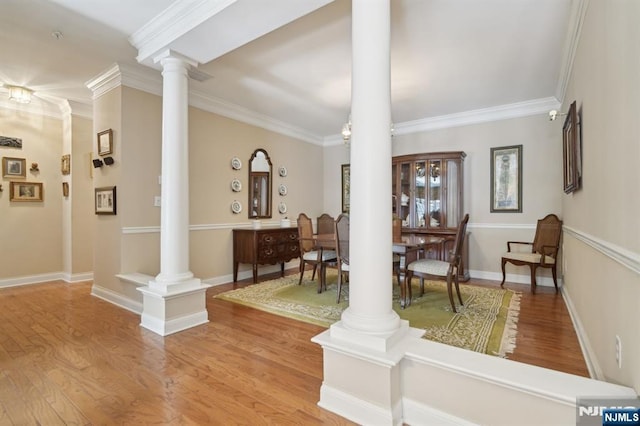 entryway featuring light wood finished floors, baseboards, crown molding, and ornate columns