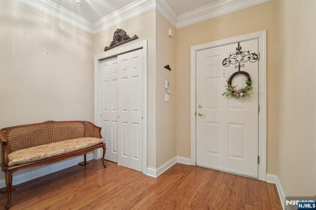 foyer entrance featuring baseboards, crown molding, and light wood-style floors