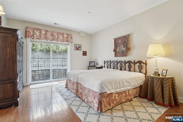 bedroom with hardwood / wood-style flooring, access to outside, and visible vents