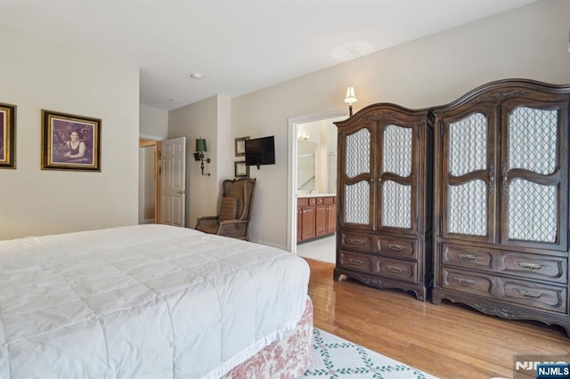 bedroom featuring ensuite bath and light wood-style flooring