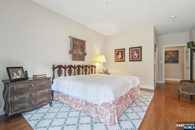 bedroom featuring visible vents, baseboards, and wood finished floors