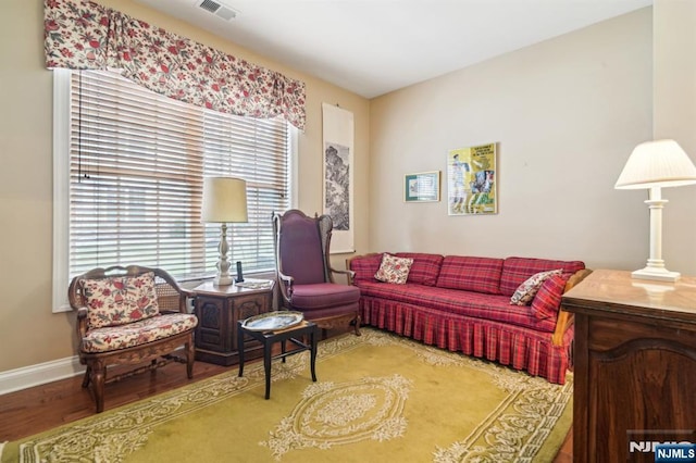 living area with visible vents, baseboards, and wood finished floors