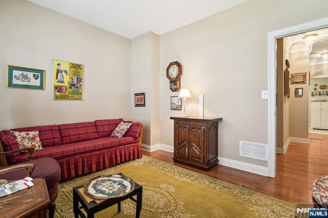 living area featuring visible vents, baseboards, and wood finished floors