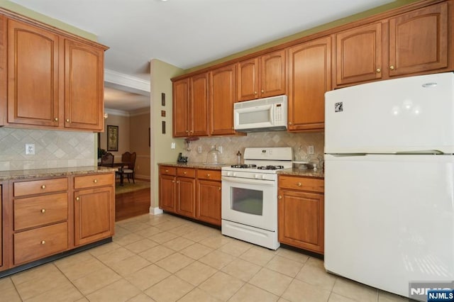 kitchen featuring white appliances, light tile patterned floors, stone counters, ornamental molding, and brown cabinets