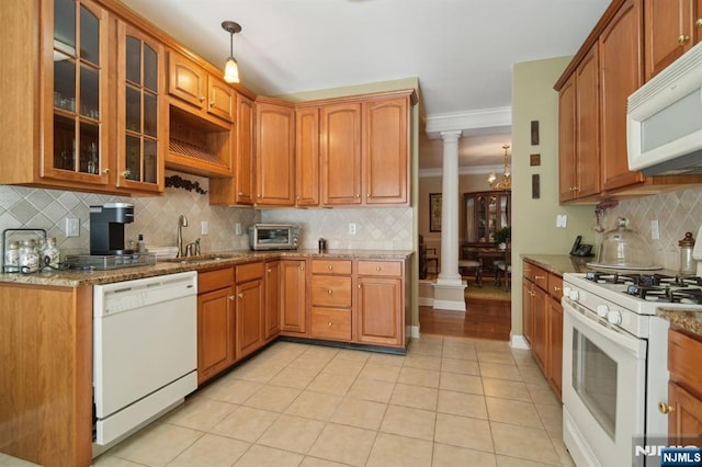 kitchen featuring crown molding, light tile patterned floors, white appliances, ornate columns, and a sink