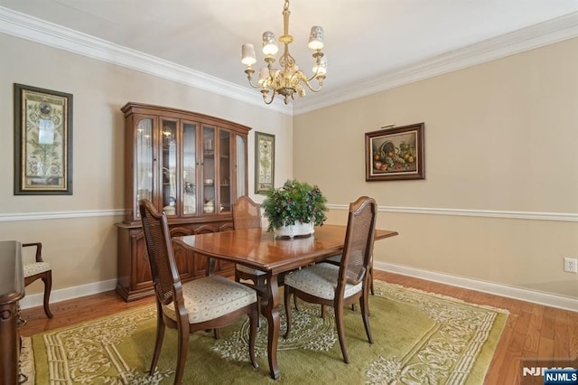 dining room featuring light wood-type flooring, baseboards, a chandelier, and crown molding