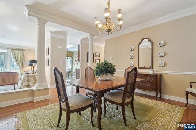 dining space featuring crown molding, decorative columns, and wood finished floors