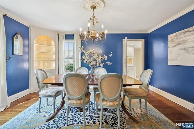 dining room with an inviting chandelier, crown molding, wood finished floors, and baseboards