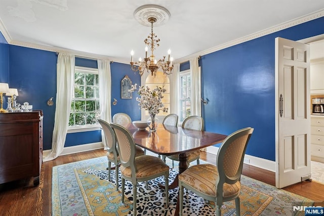 dining area featuring a chandelier, wood finished floors, baseboards, and ornamental molding