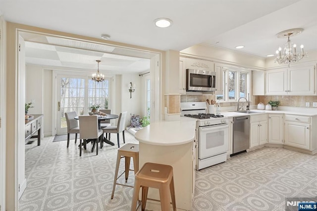 kitchen with a notable chandelier, a sink, appliances with stainless steel finishes, a peninsula, and light countertops