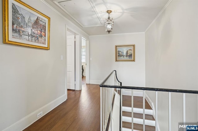 corridor with attic access, wood finished floors, an upstairs landing, and ornamental molding