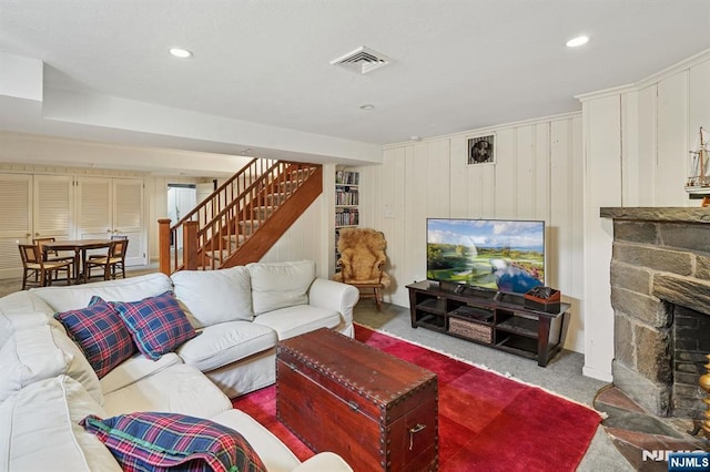 carpeted living room featuring a stone fireplace, stairway, recessed lighting, and visible vents