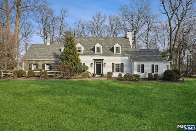 new england style home featuring a front yard and a chimney