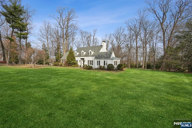 view of front facade featuring a chimney and a front lawn